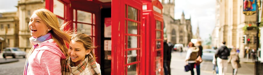 イギリスの公衆電話ボックスの横に立つ 2 人の少女