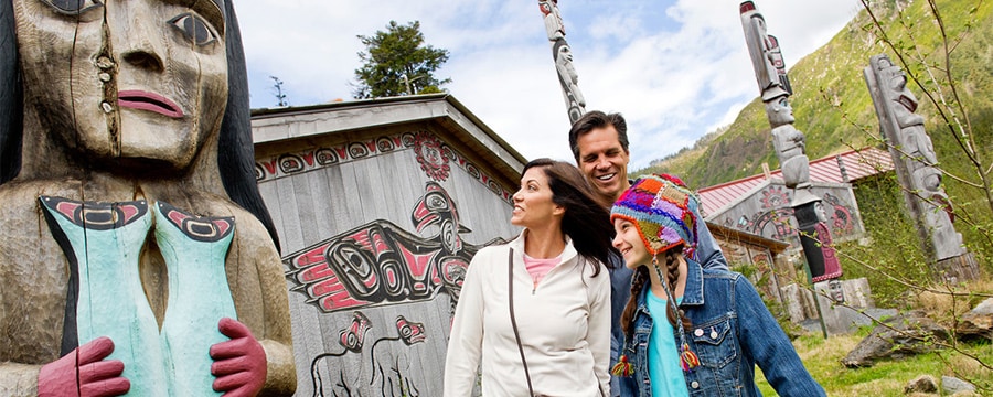 ネイティブアメリカンの伝統的なトーテムポールと建物の側に立っている家族連れ